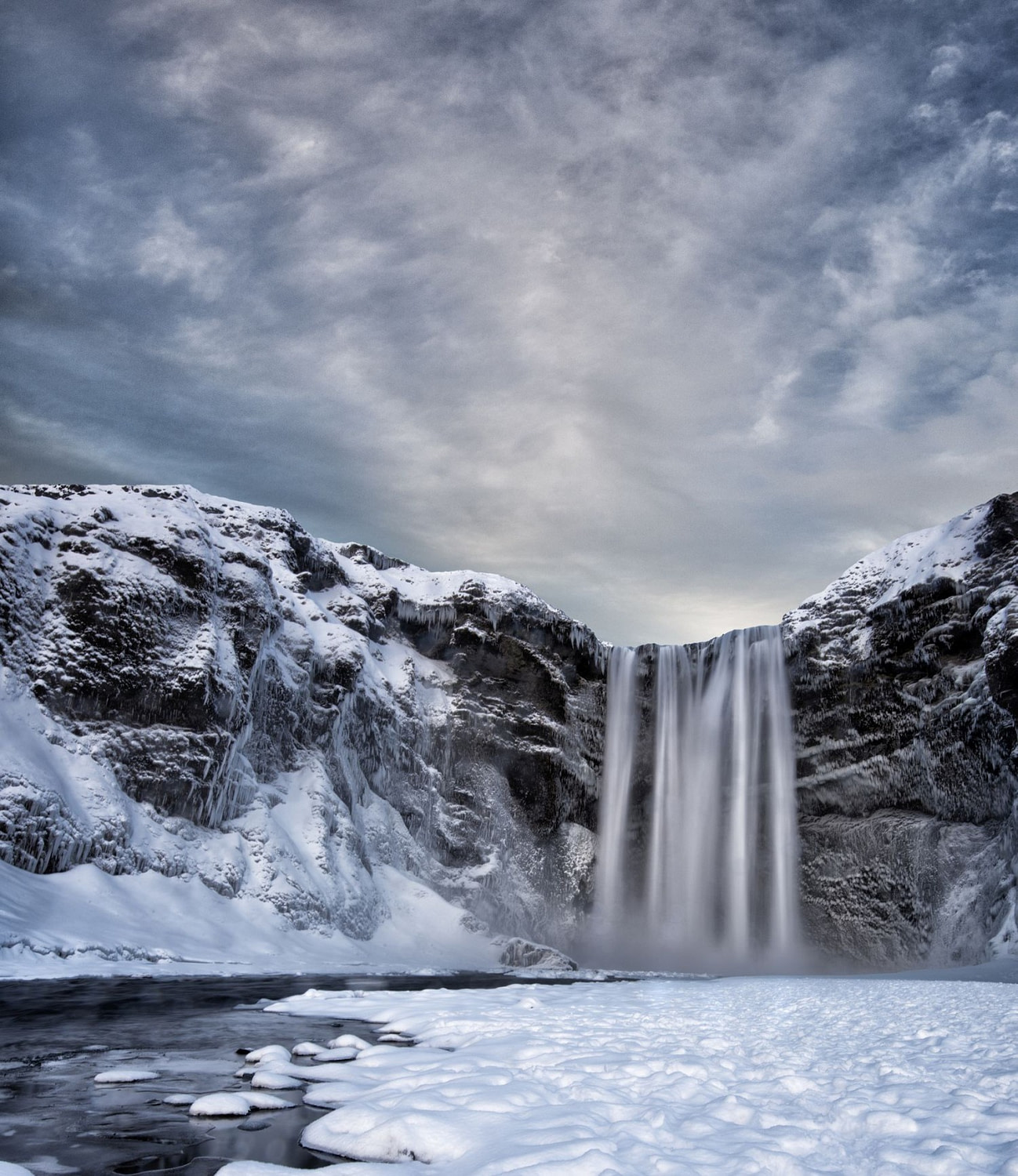 Водопад зимой. Skogafoss Исландия зимой. Водопады Исландии зима. Зимний водопад. Водопад в снежных горах.